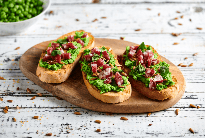 Toasted bread with peas cream, sunflower seeds and salame